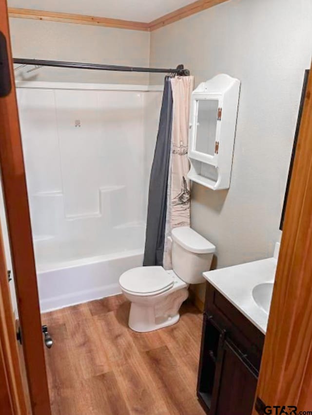 full bathroom featuring ornamental molding, vanity, shower / bath combo with shower curtain, hardwood / wood-style flooring, and toilet