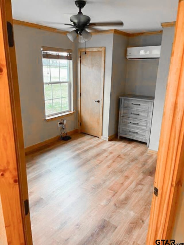 unfurnished bedroom featuring a wall mounted air conditioner, light hardwood / wood-style floors, and crown molding