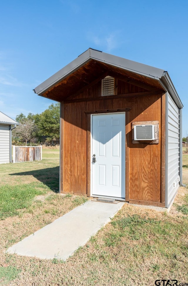 view of outdoor structure with a wall mounted air conditioner and a yard