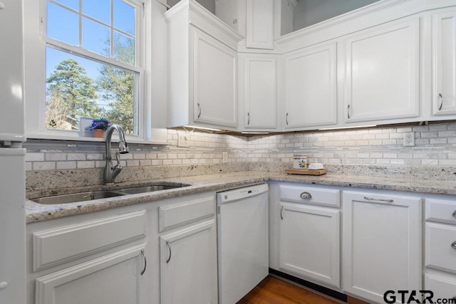 kitchen featuring tasteful backsplash, white dishwasher, a sink, and white cabinets