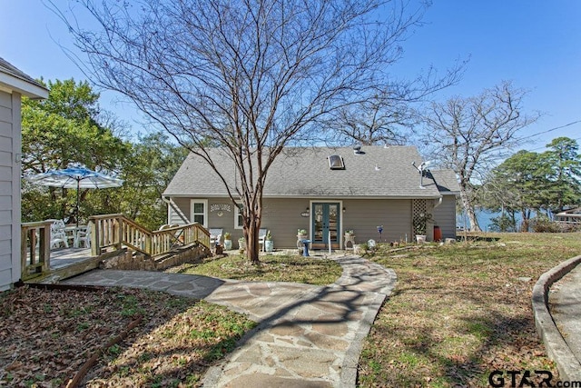 rear view of property featuring a shingled roof, french doors, and a wooden deck