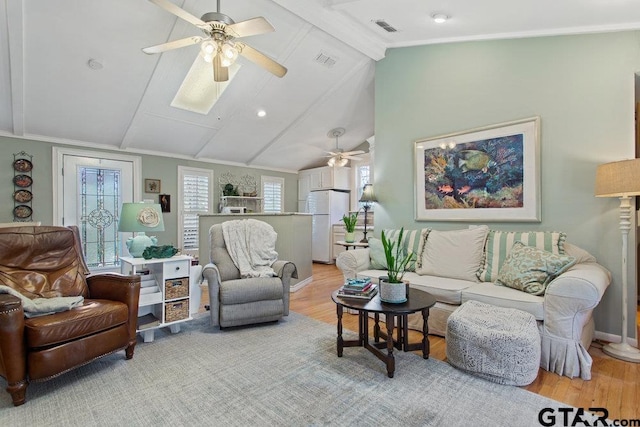 living room featuring lofted ceiling with beams, visible vents, and light wood-style floors