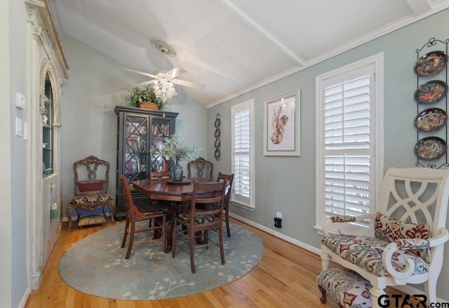 dining room featuring ceiling fan, wood finished floors, baseboards, vaulted ceiling, and ornamental molding