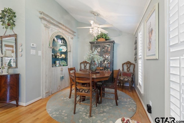 dining area featuring a ceiling fan, baseboards, vaulted ceiling, and wood finished floors