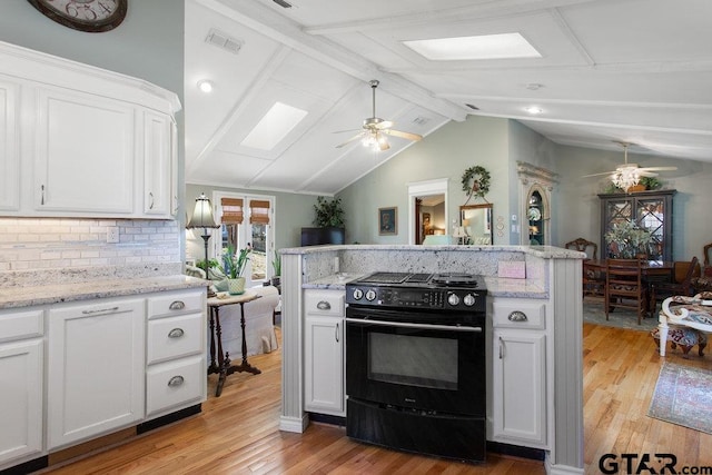 kitchen featuring black electric range oven, a ceiling fan, light wood-style floors, lofted ceiling with skylight, and white cabinetry