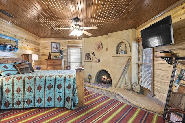 bedroom with ceiling fan, wooden walls, and wooden ceiling