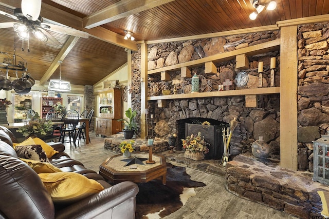 living room featuring ceiling fan, vaulted ceiling with beams, a stone fireplace, and hardwood / wood-style floors