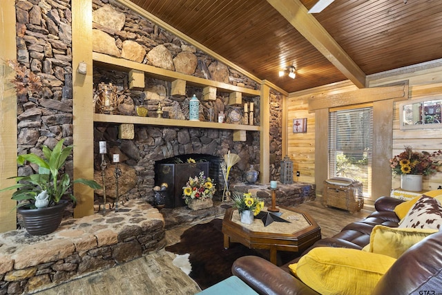 living room featuring wooden walls, hardwood / wood-style flooring, a stone fireplace, and lofted ceiling with beams