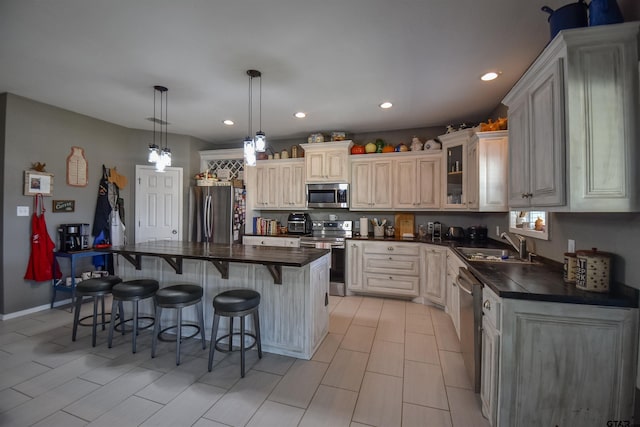 kitchen featuring a breakfast bar area, stainless steel appliances, a sink, dark countertops, and glass insert cabinets