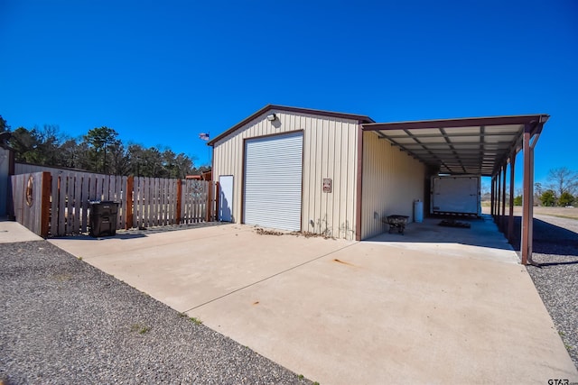 view of outbuilding with an outbuilding, driveway, and fence