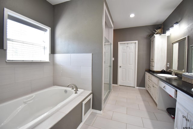 bathroom with a stall shower, vanity, a bath, baseboards, and tile patterned floors