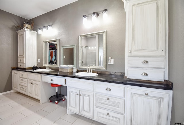 full bathroom featuring a shower with shower door, a sink, and double vanity