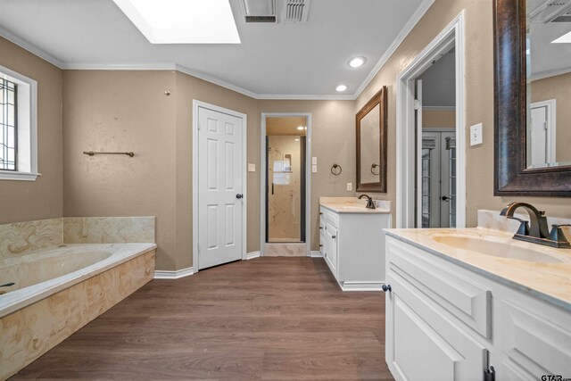 5806 Plantation Dr, Tyler, TX 75703 - bathroom featuring wood finished floors, a stall shower, two vanities, a garden tub, and ornamental molding
