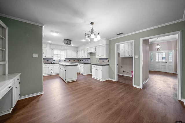 5806 Plantation Dr, Tyler, TX 75703 - kitchen with a chandelier, white cabinetry, dark wood finished floors, a kitchen island, and baseboards