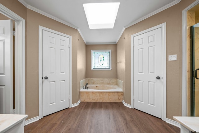 5806 Plantation Dr, Tyler, TX 75703 - bathroom featuring wood finished floors, a garden tub, ornamental molding, a skylight, and baseboards