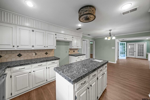 5806 Plantation Dr, Tyler, TX 75703 - kitchen featuring ornamental molding, white cabinets, dark wood finished floors, backsplash, and a kitchen island