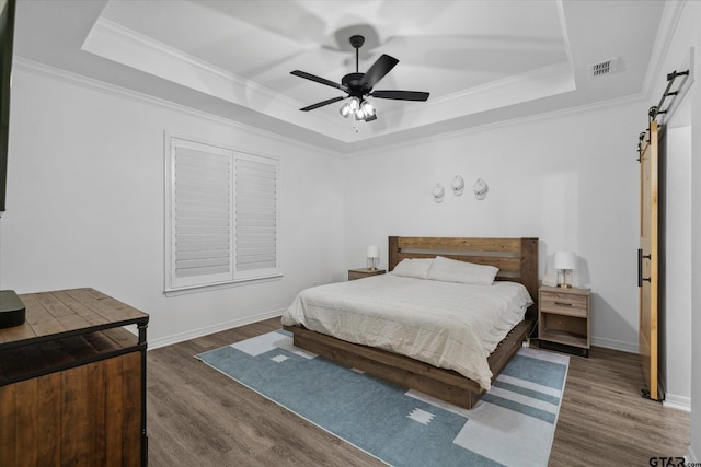 2736 Royal Village Way, Tyler, TX 75701 - bedroom with a barn door, a tray ceiling, wood finished floors, ornamental molding, and ceiling fan