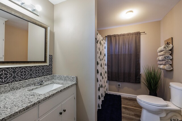 bathroom featuring tasteful backsplash, walk in shower, vanity, wood-type flooring, and toilet