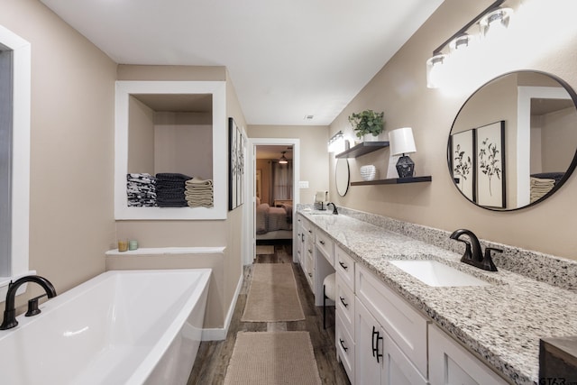 bathroom with vanity, wood-type flooring, and a bath