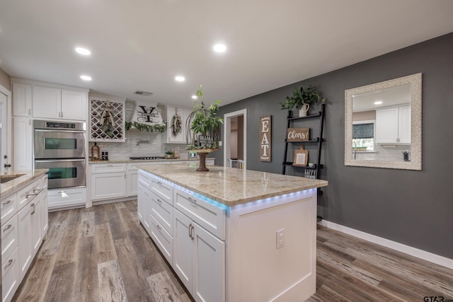 kitchen with double oven, white cabinetry, and a kitchen island