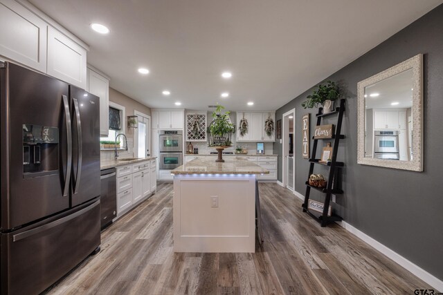 kitchen with white cabinets, a kitchen island, wood-type flooring, and stainless steel appliances