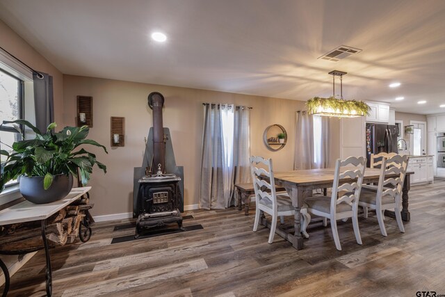 dining space with an inviting chandelier, wood-type flooring, and a wood stove