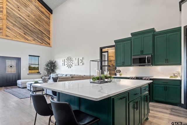 kitchen featuring a kitchen island, light wood-type flooring, high vaulted ceiling, and green cabinetry