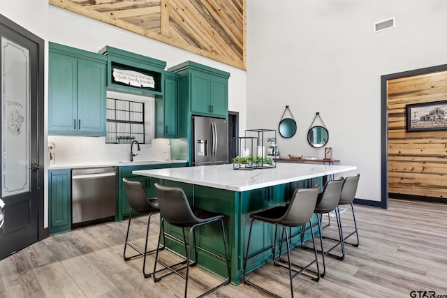 kitchen featuring a breakfast bar, a center island, high vaulted ceiling, light wood-type flooring, and stainless steel appliances