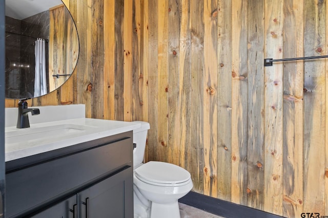 bathroom with a shower with curtain, vanity, toilet, and wooden walls