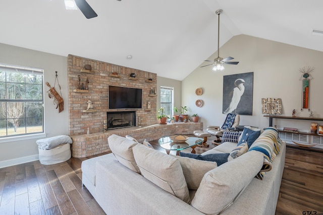 living room with a wealth of natural light, dark hardwood / wood-style flooring, ceiling fan, and a brick fireplace