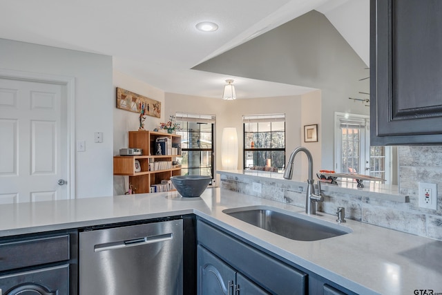 kitchen with tasteful backsplash, stainless steel dishwasher, vaulted ceiling, sink, and blue cabinetry