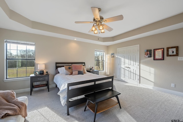 bedroom with a tray ceiling, ceiling fan, and light colored carpet