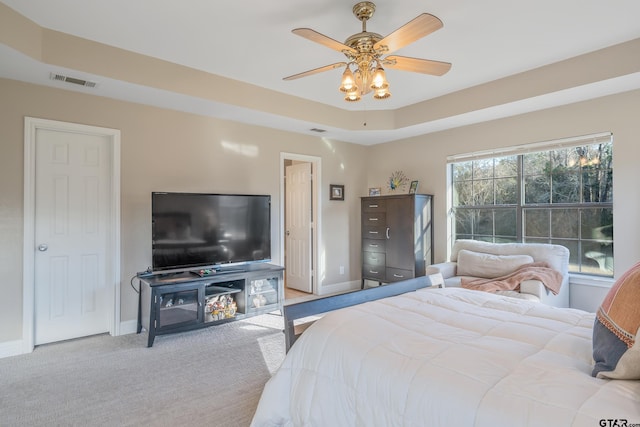 bedroom featuring light carpet, a tray ceiling, and ceiling fan