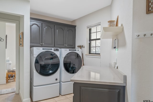 laundry room featuring washer and clothes dryer, cabinets, and light tile patterned floors