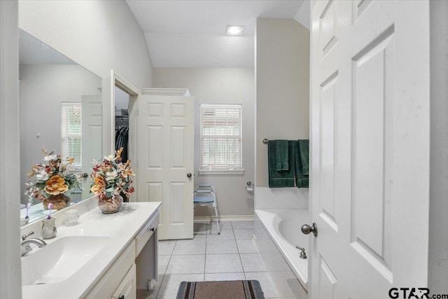 bathroom with tile patterned flooring, plenty of natural light, a tub to relax in, and vanity