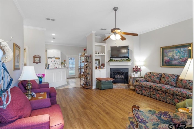 living room featuring ceiling fan, ornamental molding, and light wood-type flooring