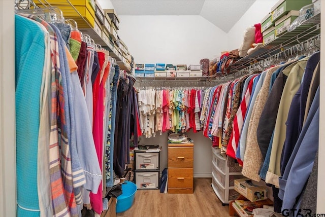 walk in closet with wood-type flooring and vaulted ceiling