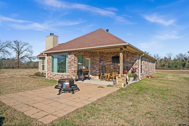 back of property featuring a yard, a patio, and a fire pit