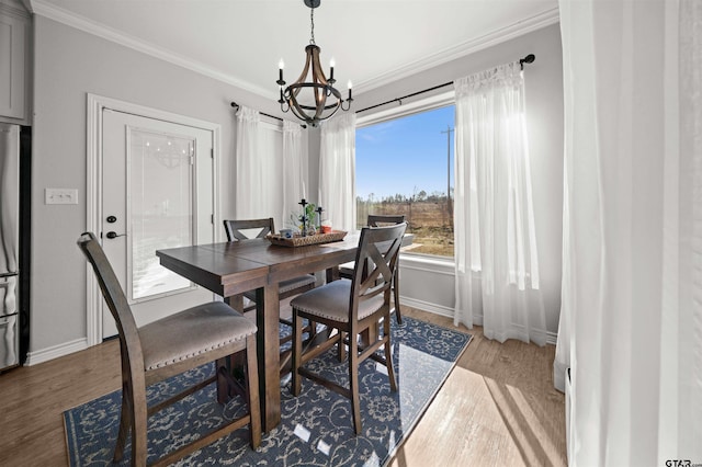 dining area featuring wood-type flooring, crown molding, and a chandelier