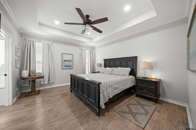 bedroom featuring a tray ceiling, multiple windows, dark wood-type flooring, and ceiling fan