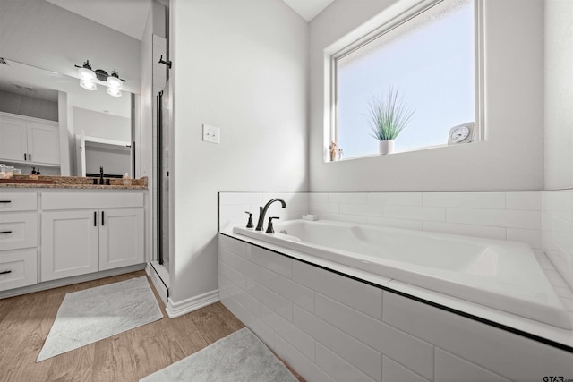 bathroom featuring tiled bath, hardwood / wood-style floors, and vanity