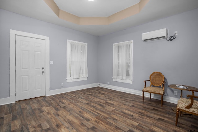 unfurnished room featuring baseboards, a wall mounted AC, dark wood finished floors, and a raised ceiling