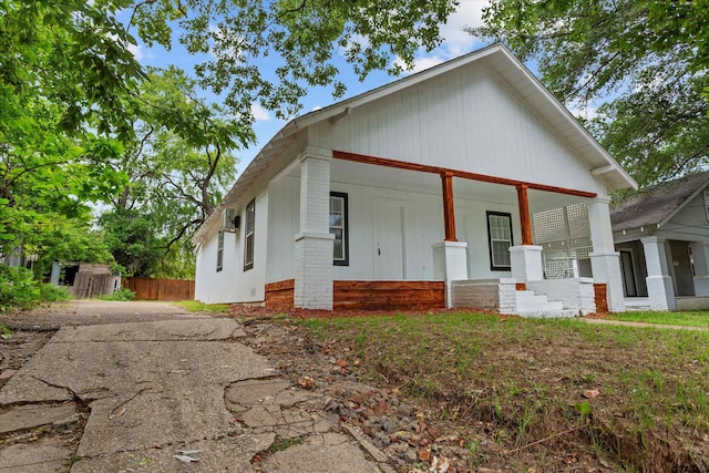 back of property with a porch, fence, driveway, and brick siding