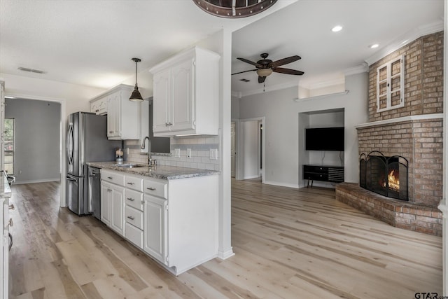 kitchen with dishwasher, sink, a brick fireplace, decorative backsplash, and white cabinetry