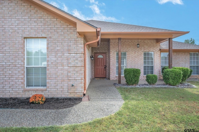 view of exterior entry with a yard