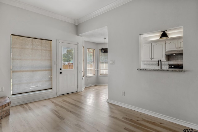 entryway featuring light wood-type flooring, crown molding, and sink