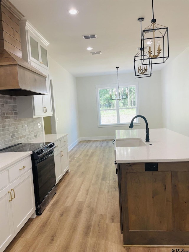 kitchen featuring white cabinetry, sink, decorative light fixtures, light hardwood / wood-style flooring, and black range with electric stovetop