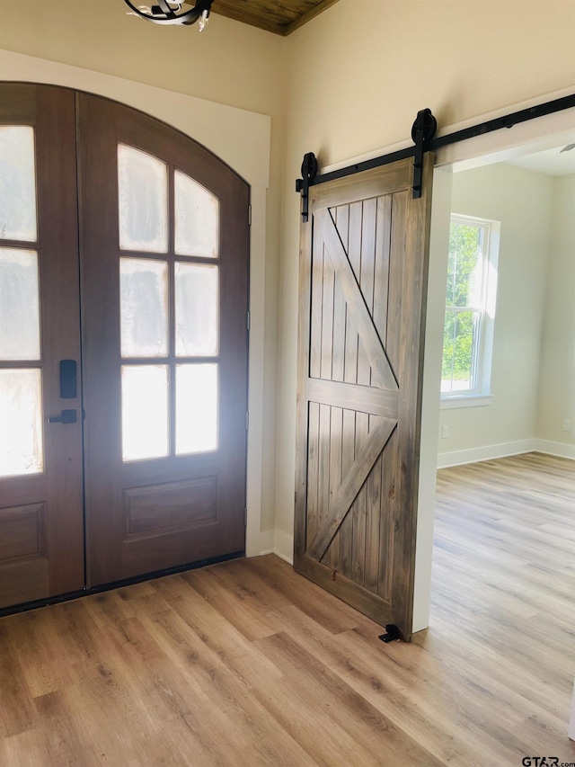 foyer with a barn door, light hardwood / wood-style floors, and french doors