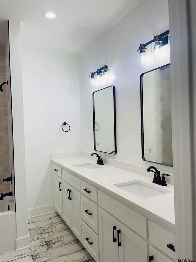 bathroom featuring hardwood / wood-style floors, vanity, and washtub / shower combination