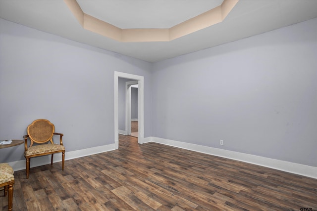 living area with dark hardwood / wood-style floors and a raised ceiling